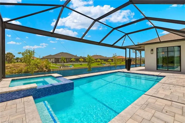 View of swimming pool featuring a patio area, glass enclosure, and an in ground hot tub