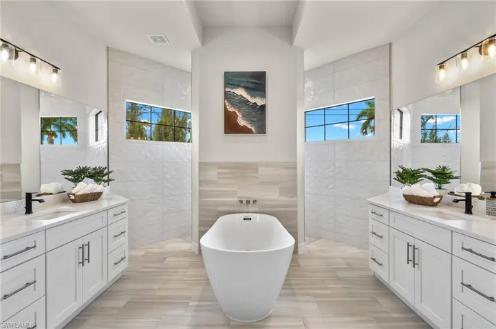 Bathroom featuring tile walls, double vanity, tile flooring, and plenty of natural light