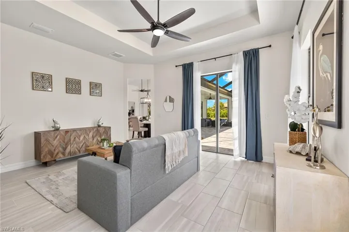 Living room featuring ceiling fan and a tray ceiling