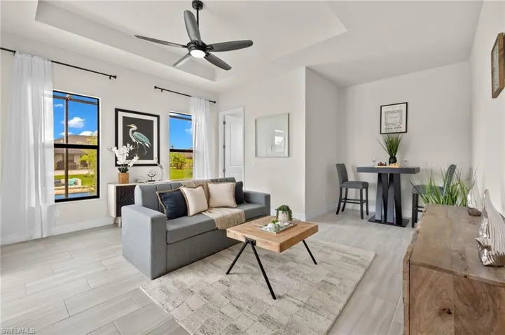 Tiled living room featuring a tray ceiling and ceiling fan