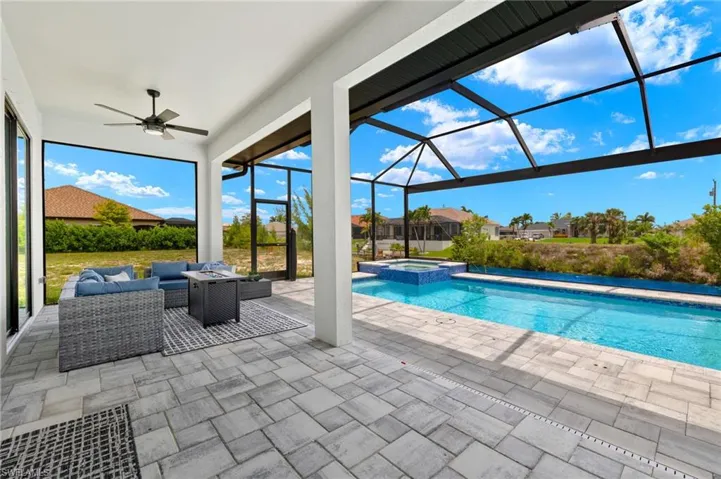 View of swimming pool featuring outdoor lounge area, glass enclosure, an in ground hot tub, a patio area, and ceiling fan
