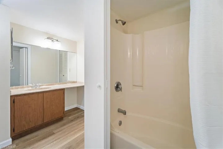 Bathroom with vanity, wood-type flooring, and shower / bathtub combination with curtain