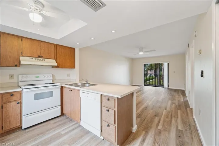 Kitchen with kitchen peninsula, ceiling fan, light wood-type flooring, sink, and white appliances