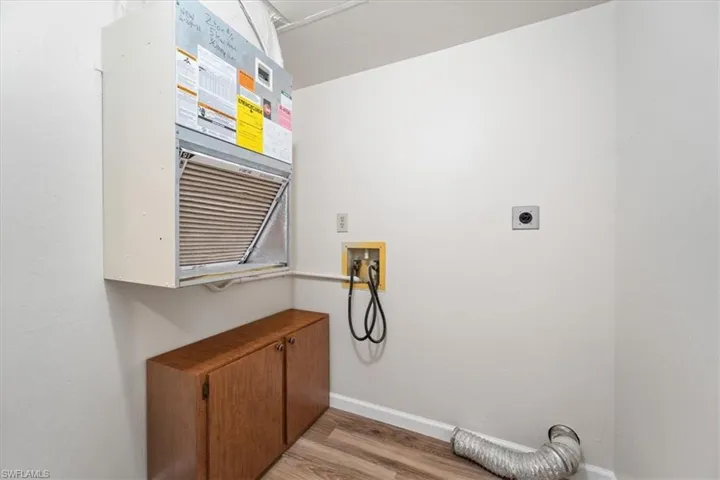 Laundry room with all necessary hookups for an electric washer and dryer with light wood-type flooring throughout the condo