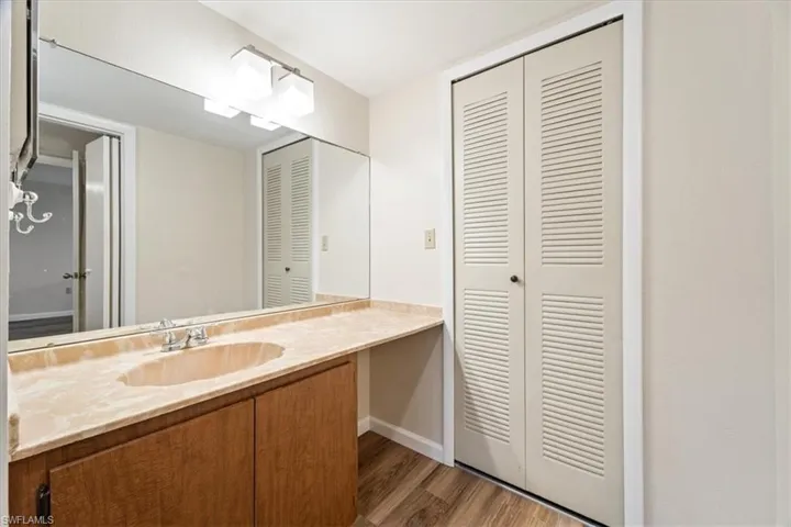Dressing room featuring a large vanity and wood-type flooring