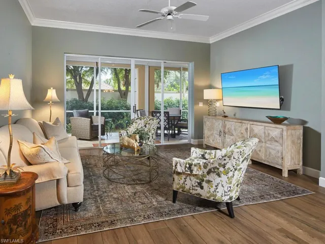 Living area with crown molding, dark wood-type flooring, and ceiling fan