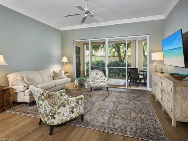 Living room with crown molding, dark wood finished floors, and ceiling fan