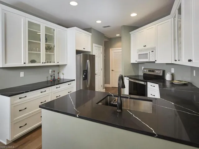 Kitchen with glass insert cabinets, dark wood finished floors, stainless steel appliances, and recessed lighting