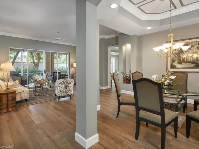 Dining room with crown molding, hardwood / wood-style flooring, a raised ceiling, recessed lighting, and a chandelier