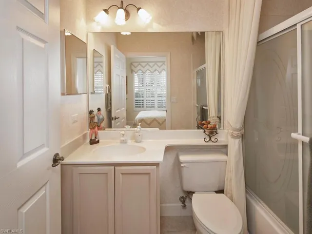 Ensuite bathroom with vanity, bath / shower combo with glass door, and a chandelier