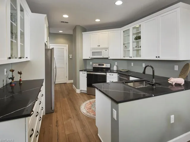 Kitchen with glass insert cabinets, stainless steel appliances, white cabinetry, dark wood-style floors, and recessed lighting
