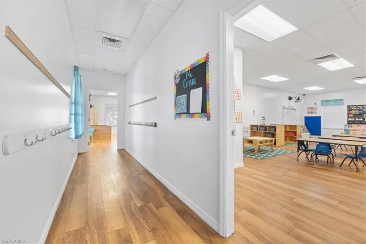Corridor with a paneled ceiling and light wood finished floors
