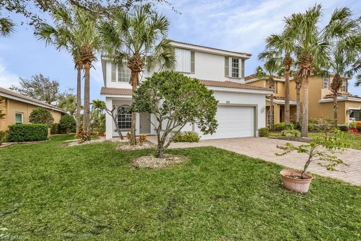 Mediterranean / spanish-style home featuring driveway, a garage, stucco siding, a tile roof, and a front lawn