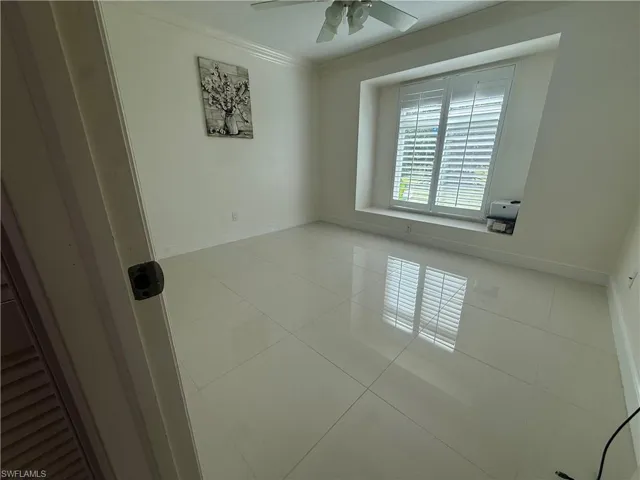 Unfurnished room featuring light tile patterned floors, crown molding, and a ceiling fan