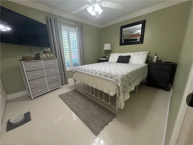 Bedroom featuring ornamental molding, light tile patterned floors, and ceiling fan