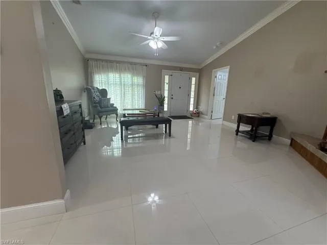 Living area featuring crown molding, light tile patterned floors, and a ceiling fan