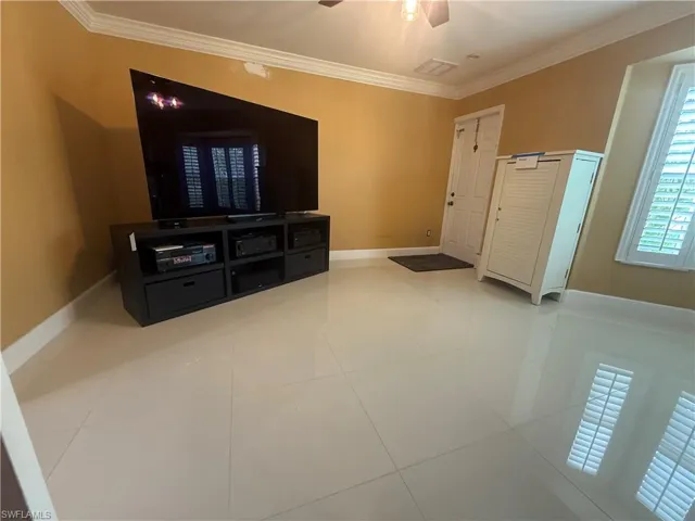 Unfurnished living room featuring crown molding, light tile patterned floors, and ceiling fan