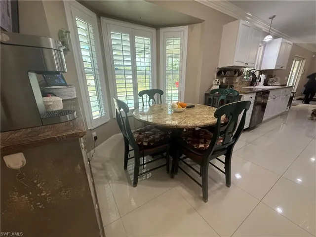 Dining space with light tile patterned floors and crown molding