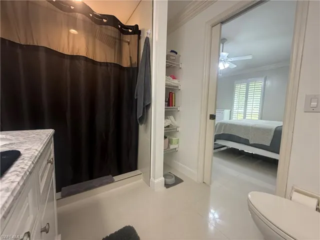 Bathroom featuring crown molding, a shower stall, light tile patterned floors, and vanity