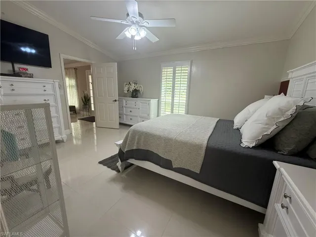 Bedroom with ornamental molding, light tile patterned floors, and a ceiling fan