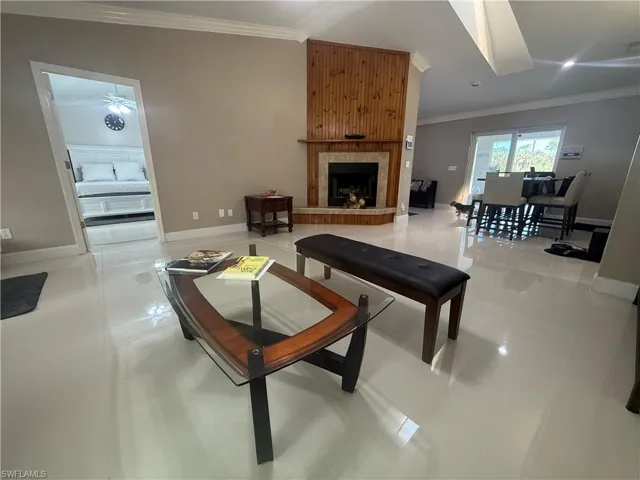 Living room with ornamental molding, a large fireplace, and light tile patterned flooring