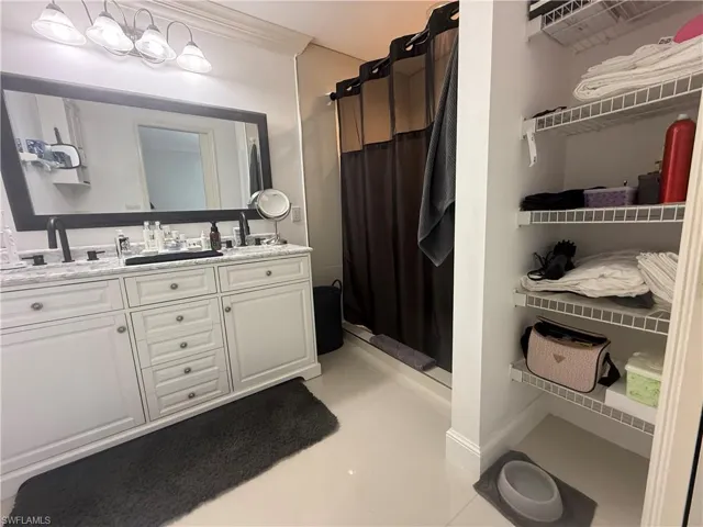 Bathroom with a stall shower, double vanity, and light tile patterned floors