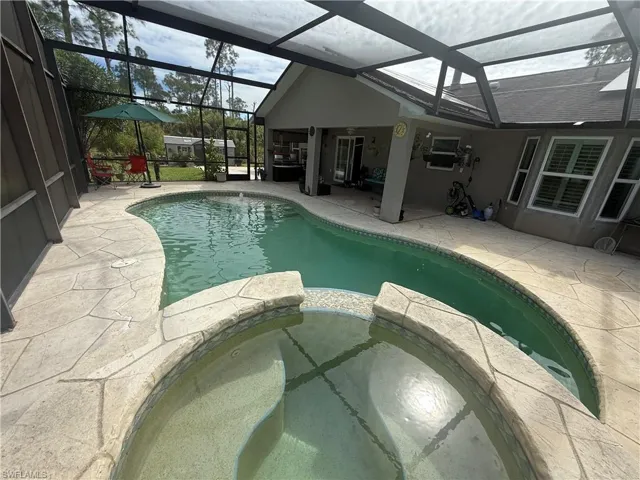 View of swimming pool with a sunroom, a patio, a pool with connected hot tub, and a lanai