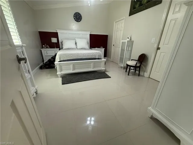 Bedroom featuring crown molding, light tile patterned floors, and a ceiling fan
