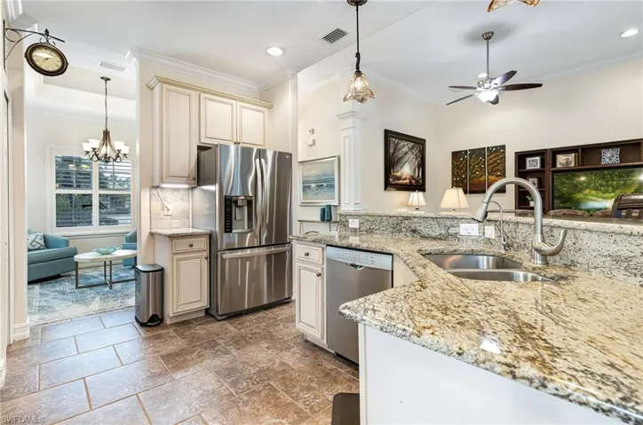 Kitchen with cream cabinets, pendant lighting, ceiling fan with notable chandelier, granite counters and  upgraded appliances with stainless steel finishes