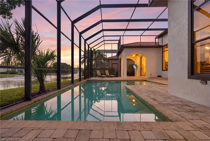 Screened lanai featuring a swimming pool, stone-paver decking, and a covered patio area