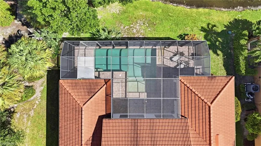 Aerial perspective featuring a tile roof, an enclosed screened lanai, a concrete paver patio, and an in-ground pool
