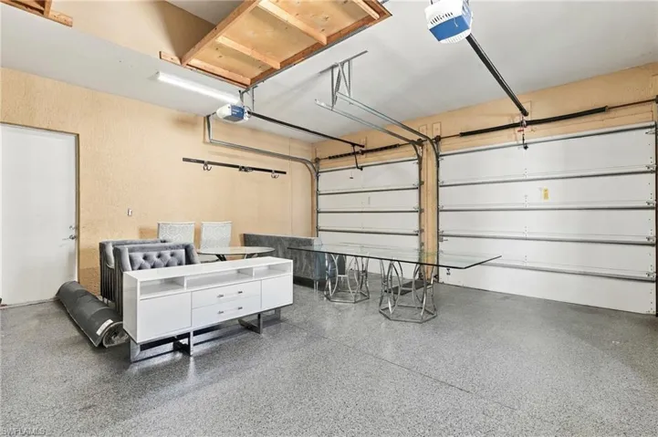 Multi-car garage featuring dual overhead sectional doors, a speckled epoxy-coated floor, and a separate side entry door