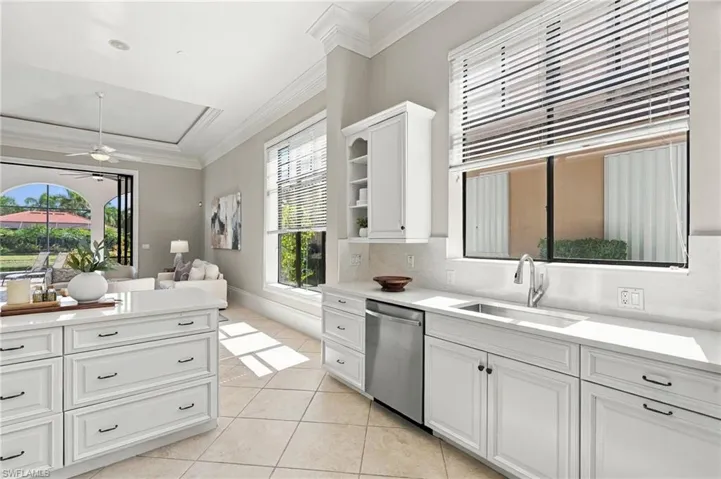 Kitchen featuring white cabinetry, center island, stone countertops, stainless steel undermount sink, and tile flooring