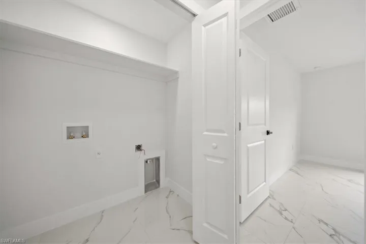 Laundry area with washer hookup, baseboards, and light marble finish flooring