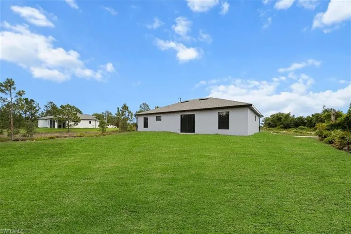 Back of house with a lawn and stucco siding