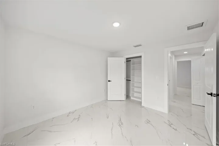 Unfurnished bedroom with baseboards, recessed lighting, light marble finish floors, a closet, and a walk in closet