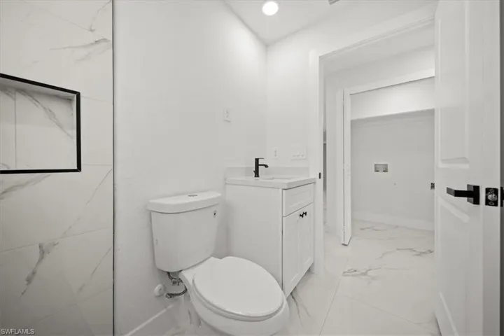 Bathroom featuring marble finish flooring, vanity, toilet, and baseboards