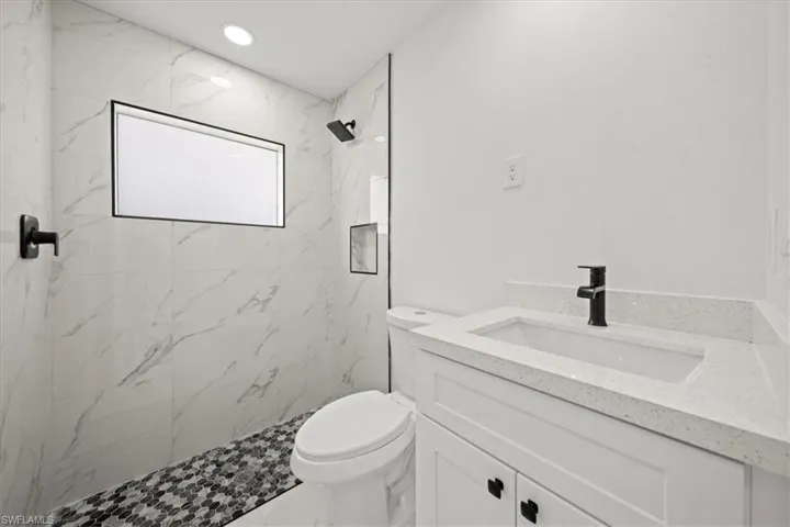 Full bathroom featuring vanity, toilet, and a marble finish shower