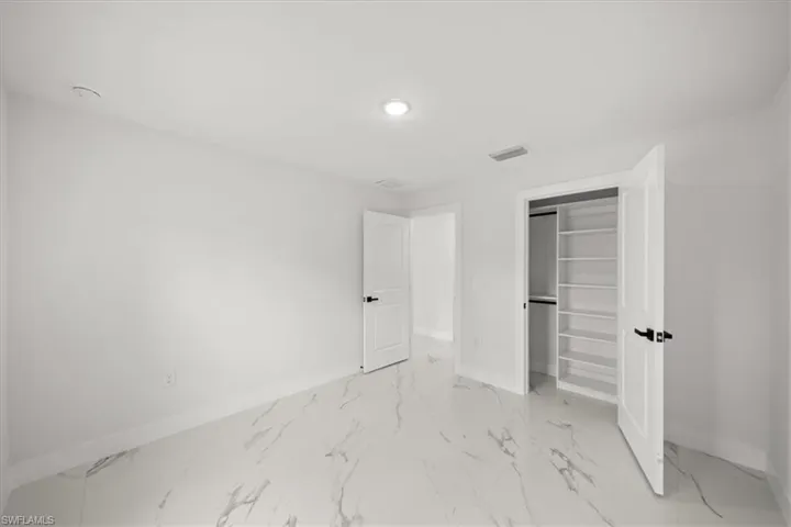 Unfurnished bedroom featuring baseboards, light marble finish flooring, recessed lighting, and a closet