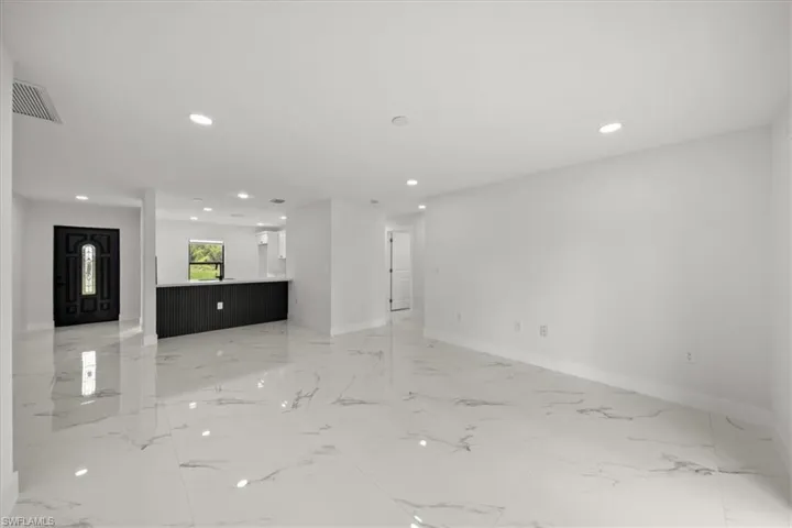Unfurnished living room with recessed lighting, baseboards, and light marble finish floors