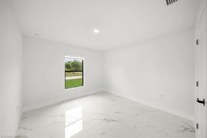 Spare room featuring light marble finish flooring, baseboards, and recessed lighting