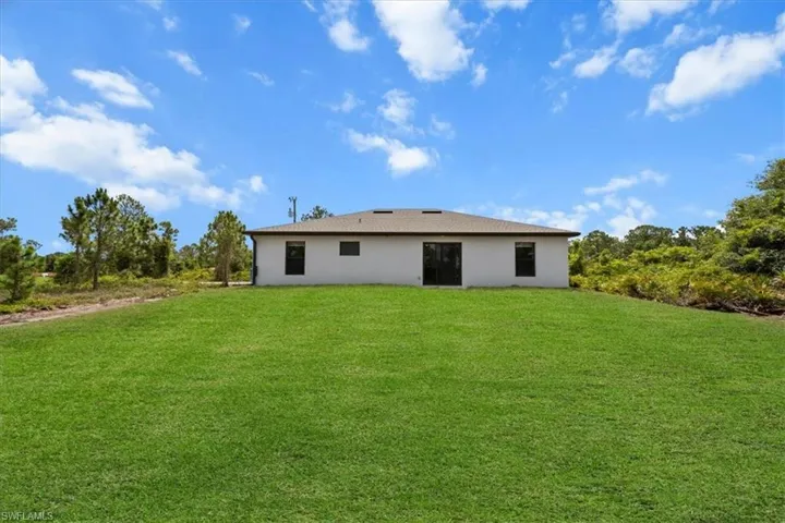 Back of house with a lawn and stucco siding