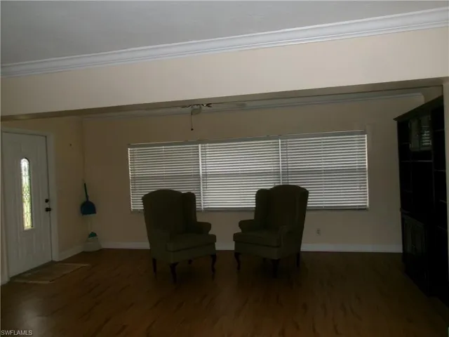 Unfurnished room featuring a healthy amount of sunlight, baseboards, ornamental molding, and dark wood-style flooring
