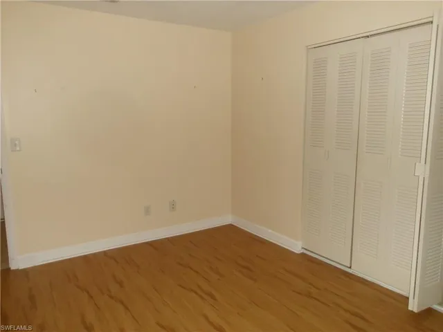 Unfurnished bedroom with a closet, wood finished floors, and baseboards