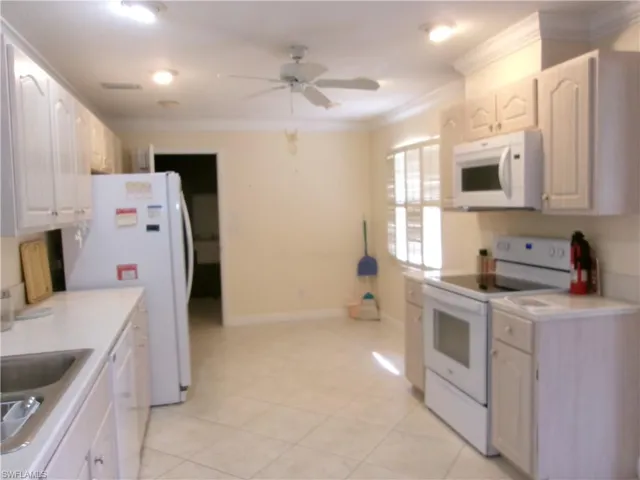Kitchen featuring ornamental molding, light countertops, white appliances, and white cabinets