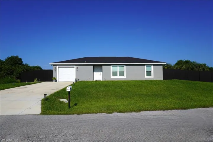 Single-story residence featuring a gray exterior, white-framed windows, and an attached garage