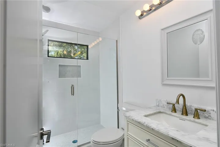 Bathroom with vanity, an enclosed shower and toilet