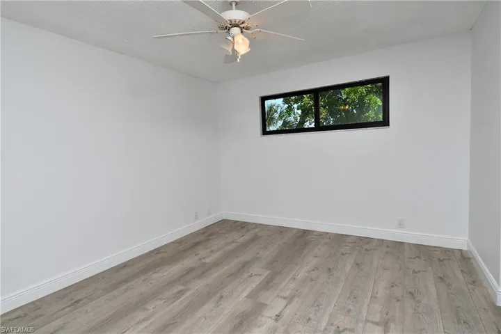 Master Bedroom featuring ceiling fan, a textured ceiling, and wood-type tile flooring and impact window.