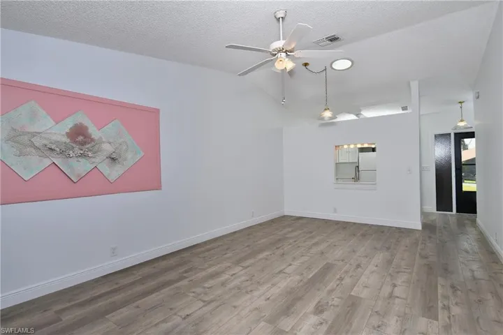Living Room/Dining Area with wood-style tile floors, a textured ceiling, ceiling fan, and lofted ceiling