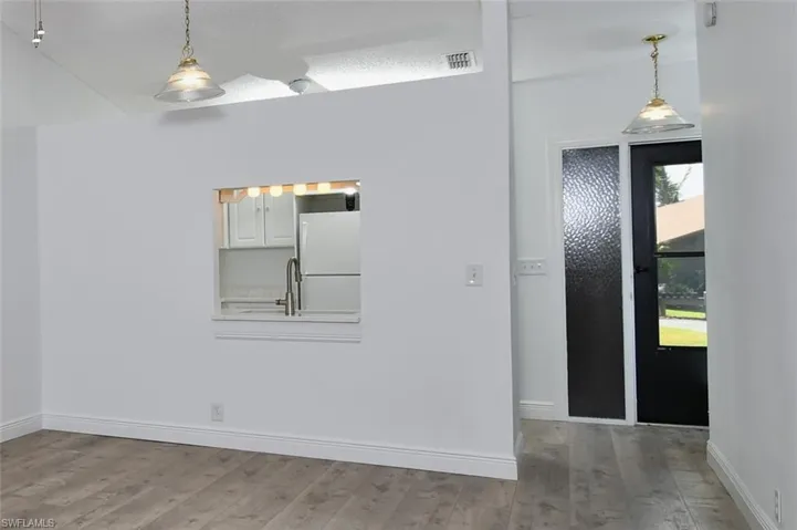 Front doorway, Dining Area, featuring a textured ceiling and tiled / wood-style flooring and pass thru from kitchen